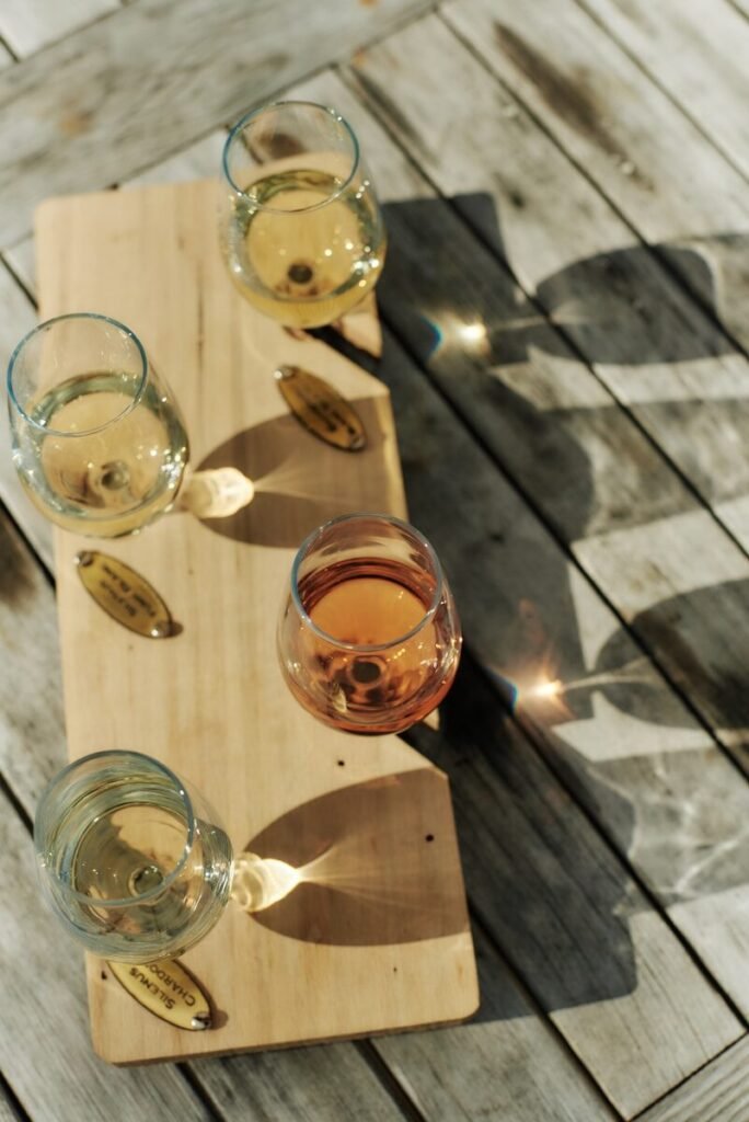 Four glasses of wine sit on a wooden board.